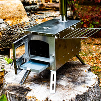 Vue avec la porte ouverte et le tiroir à cendres ouvert du mini poêle à bois pour tiny house